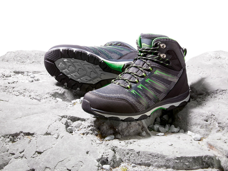 Zwei schwarze Wanderschuhe mit grünen Akzenten auf einem felsigen Untergrund.