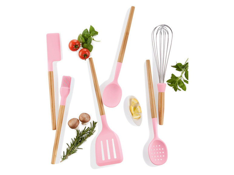 Rosa Küchenutensilien, darunter ein Schneebesen, eine Spatel und eine Schöpfkelle, mit Zutaten wie Tomaten und Basilikum.