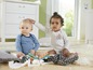 Zwei Babys spielen mit Spielzeug auf einem Teppich.