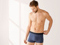 Mann in dunkelblauen Boxershorts mit Streifen.