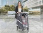 Eine Frau mit einem Regenschutz für einen Kinderwagen im Regen.