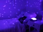 Ein Kind schläft in einem Bett mit einem Sternenprojektor und einer Schildkröten-Nachtlampe.