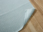 Ein hellblauer Teppich mit Zickzackmuster auf einem Holzboden.