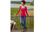 Eine Frau trägt ein rotes Langarmshirt und blaue Jeans.