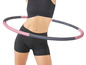 Eine Frau in Sportkleidung benutzt einen rosa-schwarzen Hula Hoop.