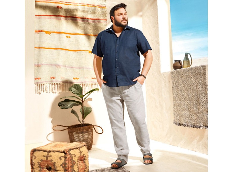 Mann in dunkelblauem Hemd und beigefarbener Hose.