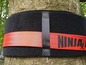 Schwarzer Klettverschluss mit rotem Ninja-Band um einen Baum.