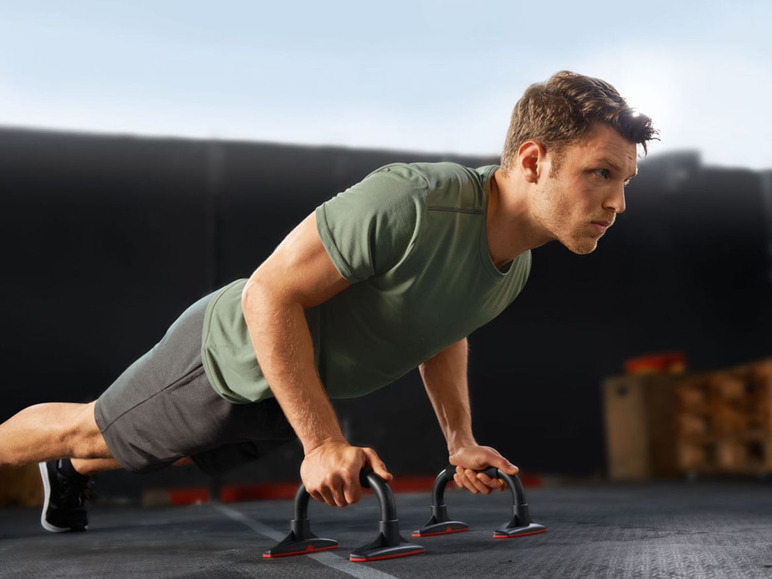 Ein Mann macht Liegestütze mit Push-up-Stangen.