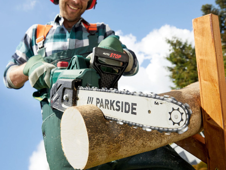 Ein Mann verwendet eine Parkside Kettensäge, um Holz zu sägen.