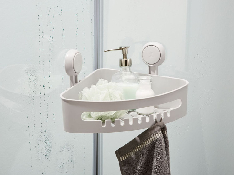 Ein Eckregal für die Dusche mit Saugnäpfen, einem Handtuch und Toilettenartikeln.