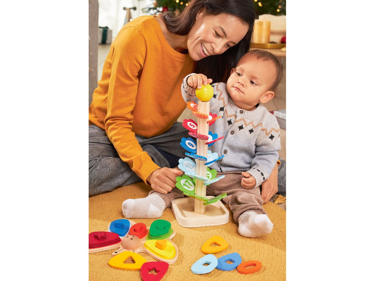 Ein Kind spielt mit Holzspielzeug in Form eines Baumes und eines Schmetterlings.