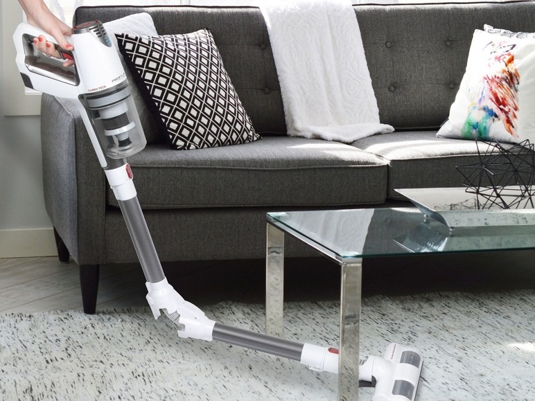 Ein kabelloser Staubsauger von Proscenic wird verwendet, um ein graues Sofa zu saugen.