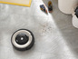Ein Roomba-Roboterstaubsauger auf einem Fliesenboden mit Schmutz.