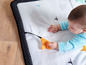 Ein Baby, das auf einer Spielmatte mit Sternen und Bäumen liegt