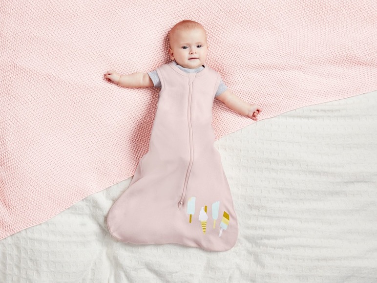 Ein Baby in einem rosa Schlafsack mit Eiscreme-Motiv.