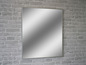 Ein rechteckiger Spiegel mit silbernem Rahmen an einer weißen Backsteinwand.