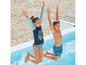 Zwei Kinder springen in ein Schwimmbecken, ein Mädchen trägt einen blauen Badeanzug mit langen Ärmeln und ein Junge trägt eine blaue Badehose.