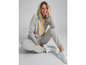 Eine Frau trägt einen grauen Hoodie und Jogginghose mit weißen Sneakern.