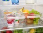 Joghurt, Obst und Gemüse in transparenten Behältern in einem Kühlschrank.