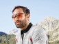 Mann mit Sonnenbrille und Fahrradkleidung schaut auf die Berge.
