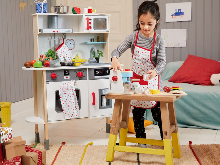 Ein Kind spielt mit einer Holzküche und einer Kaffeemaschine.