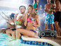 Eine Gruppe von Menschen genießt eine Party am Pool mit einem tragbaren Lenco-Lautsprecher.