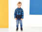 Ein Junge trägt eine blaue Tarnjacke und Jeans.