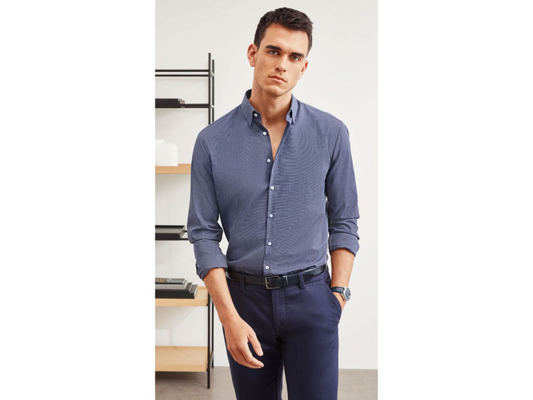 Mann in einem dunkelblauen Hemd und einer dunkelblauen Hose.