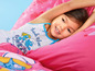 Ein Mädchen im Bett mit Smurfen-Bettwäsche und einem Smurfen-Tanktop.