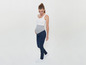 Schwangeres Model trägt ein weißes Top und blaue Jeans.