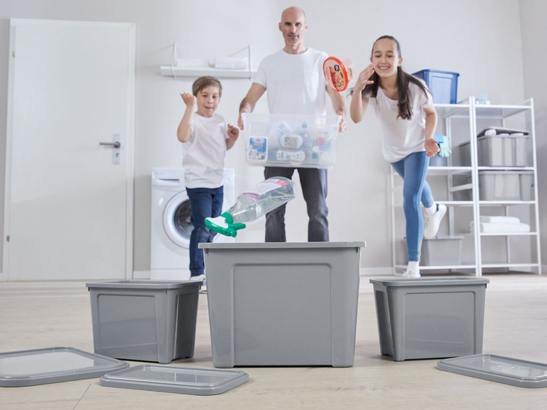 Drei graue Aufbewahrungsboxen mit Deckeln, ein Mann und zwei Kinder im Hintergrund.