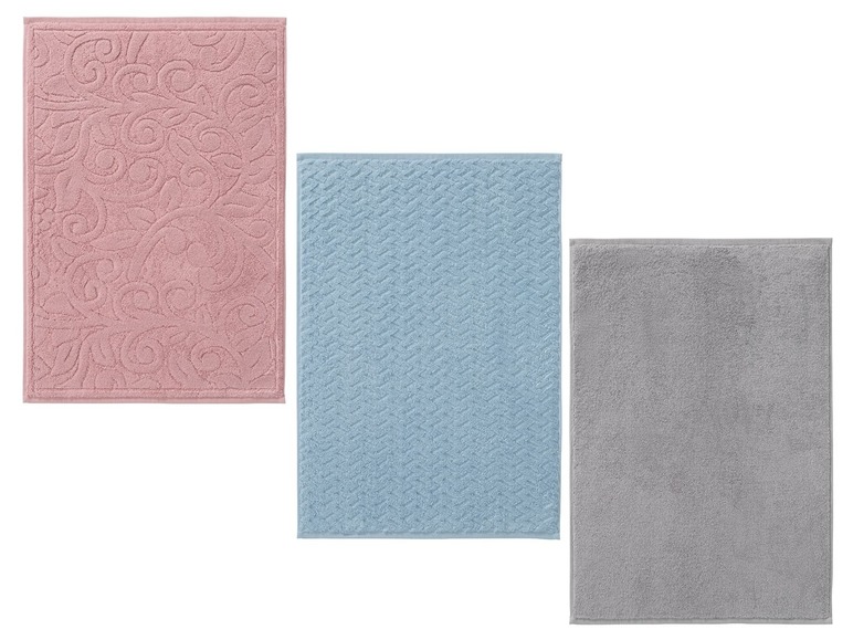 Drei Badematten: rosa mit Muster, blau kariert und grau.