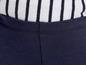 Detail einer dunkelblauen Hose mit einer weißen gestreiften Bluse darunter.