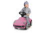 Ein Kind fährt ein rosafarbenes Volkswagen Beetle Spielzeugauto.