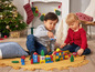 Zwei Kinder spielen mit Holzklötzen und Spielzeugautos zu Weihnachten.