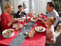 Eine Familie isst an einem festlich gedeckten Tisch mit gebackenen Äpfeln.