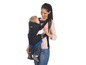 Eine Frau trägt ein Baby in einer Safety 1st Tragehilfe.
