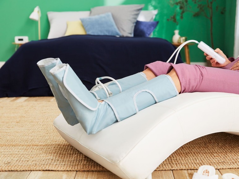 Eine Frau verwendet ein Gerät zur Kompressionstherapie an ihren Beinen.