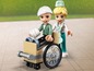 Eine LEGO-Figur im Rollstuhl wird von einer LEGO-Krankenschwester geholfen.