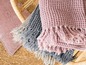 Rosa, graue und beige gestrickte Decken mit Fransen.