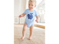 Baby in einem blauen Strampler mit dem Aufdruck 'Growing' auf einem Apfel.