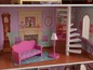 Ein rosa Sofa, eine Treppe und eine Uhr in einem Puppenhaus.