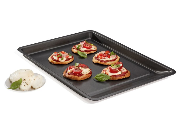 Mini-Pizzen auf einem Backblech mit Mozzarella und Basilikum