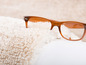 Eine braune Brille auf einem flauschigen, weißen Teppich.