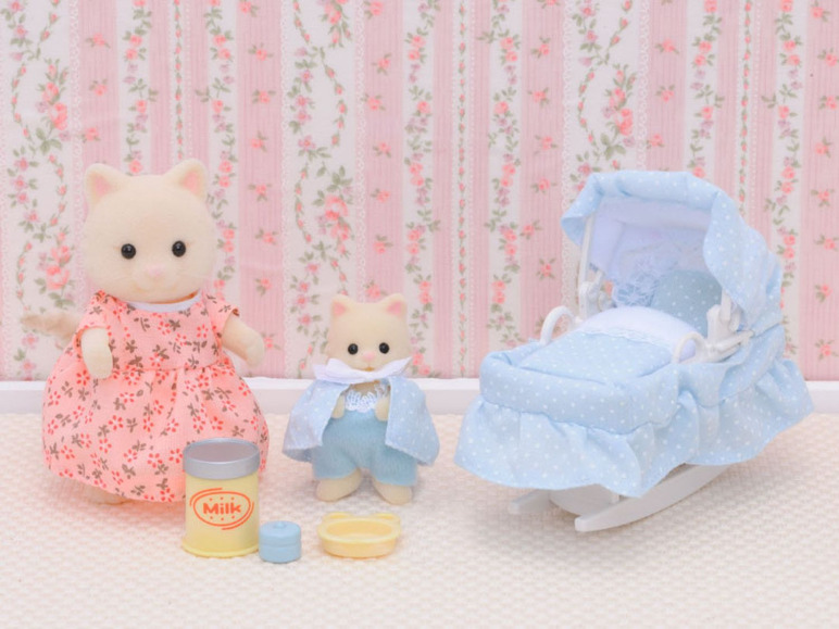 Zwei Puppen, ein Babybett und Zubehör zum Puppenspielen.