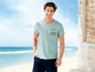 Mann in einem hellblauen T-Shirt mit Miami-Druck am Strand.