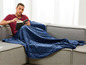 Mann liest auf der Couch unter einer blauen Gewichtsdecke.