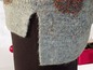 Ein grauer Strickpullover mit Glitzerdetails, neben rotem Geschenkpapier.