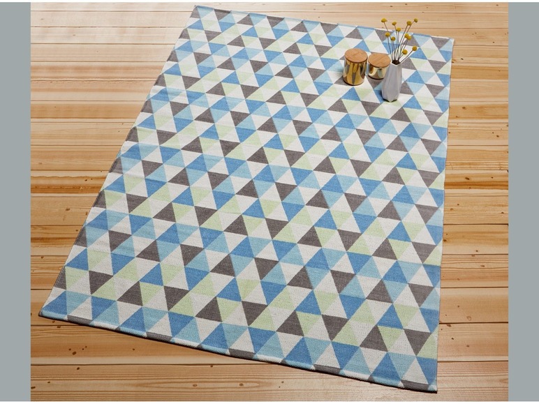 Ein Teppich mit einem geometrischen Muster in Blautönen, Grün- und Grautönen.