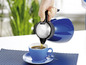 Eine blaue Thermoskanne gießt Kaffee in eine blaue Tasse.